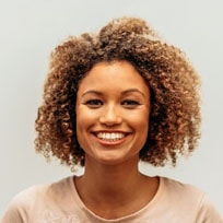 woman with large hair smiling and showing straight white teeth from cosmetic dentistry treatment