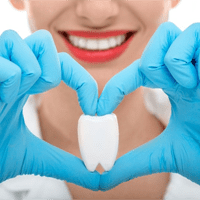 post-dental-op instructions, hygienist holding fake tooth with heart shaped hands